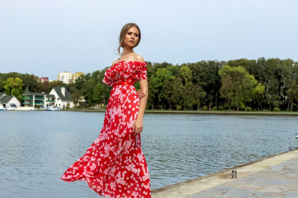 Femeie în rochie roșie florală lângă lac