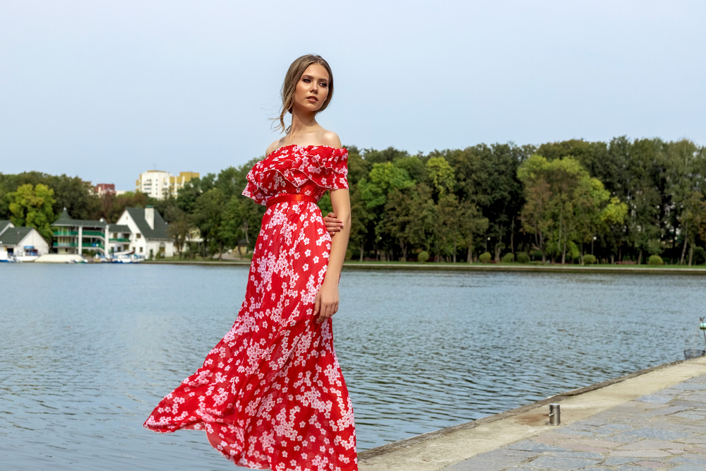 Femeie în rochie roșie florală lângă lac