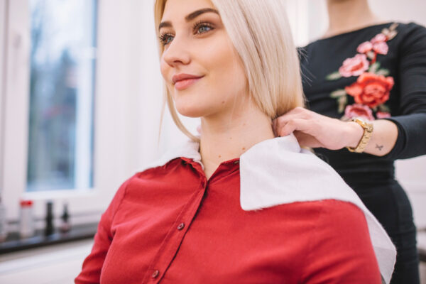 Femeie la salon, stilistă pune prosop pe umeri